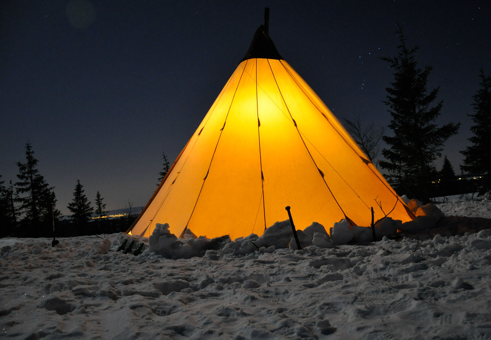 Tipi installé de nuit dans un paysage enneigé